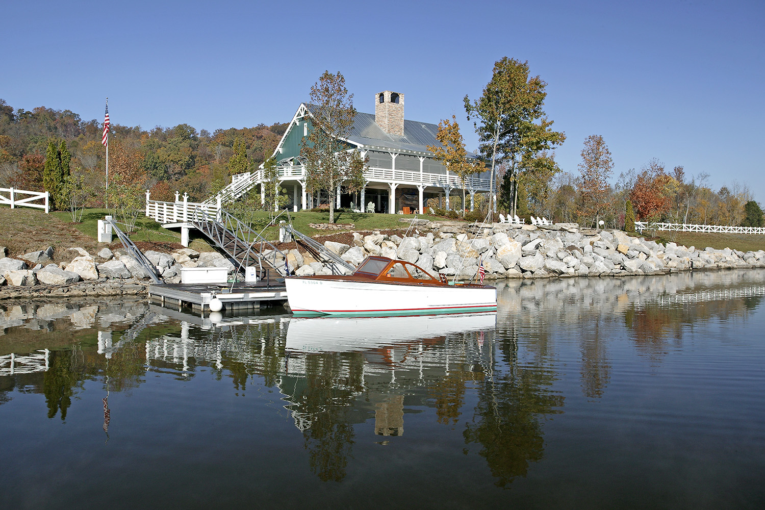 A lakeside residence with a covered porch, a wooden boat moored below.