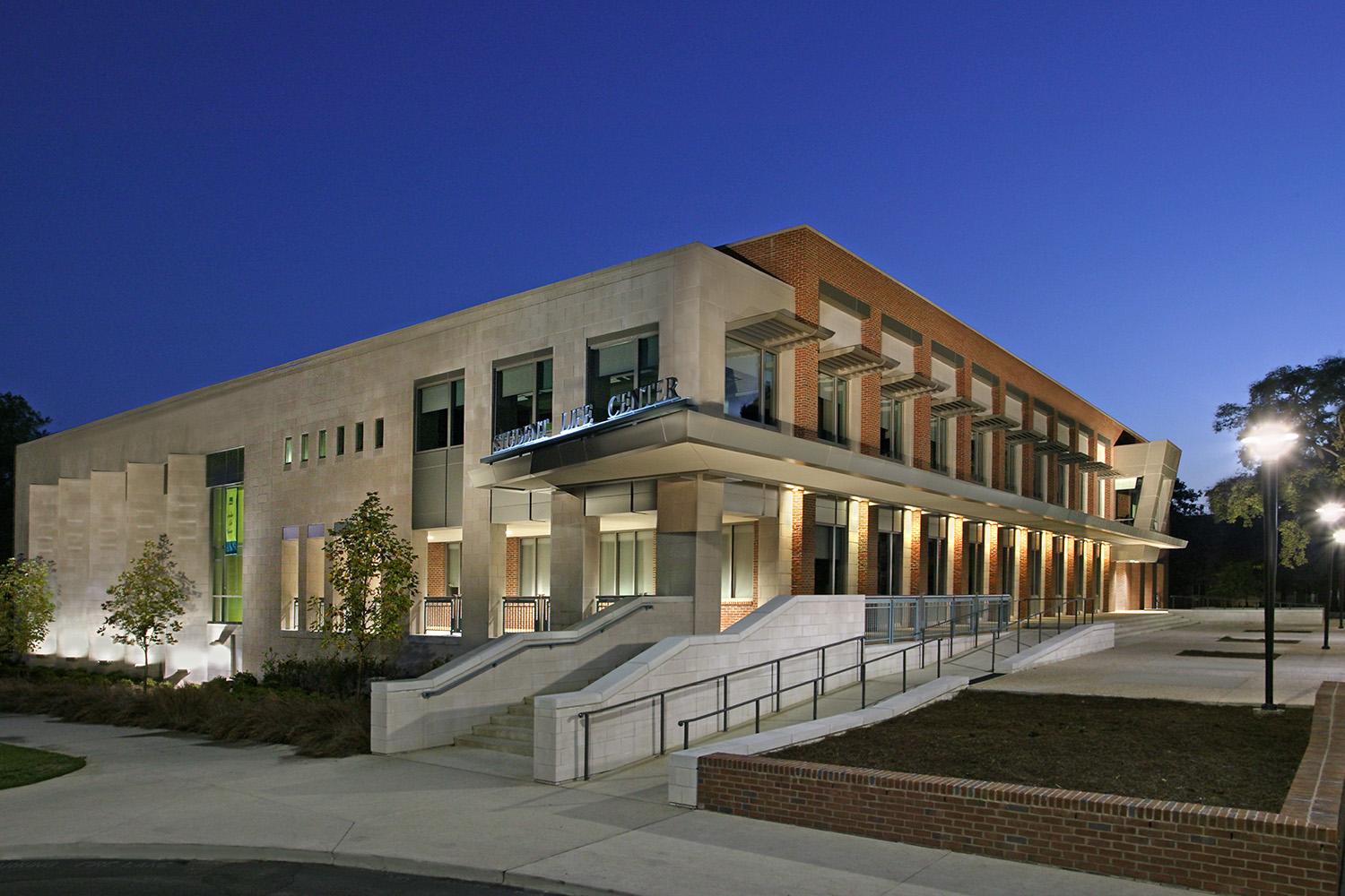 The Student Life Center at Vanderbilt University at dusk, its limestone and brick facade lit from within.