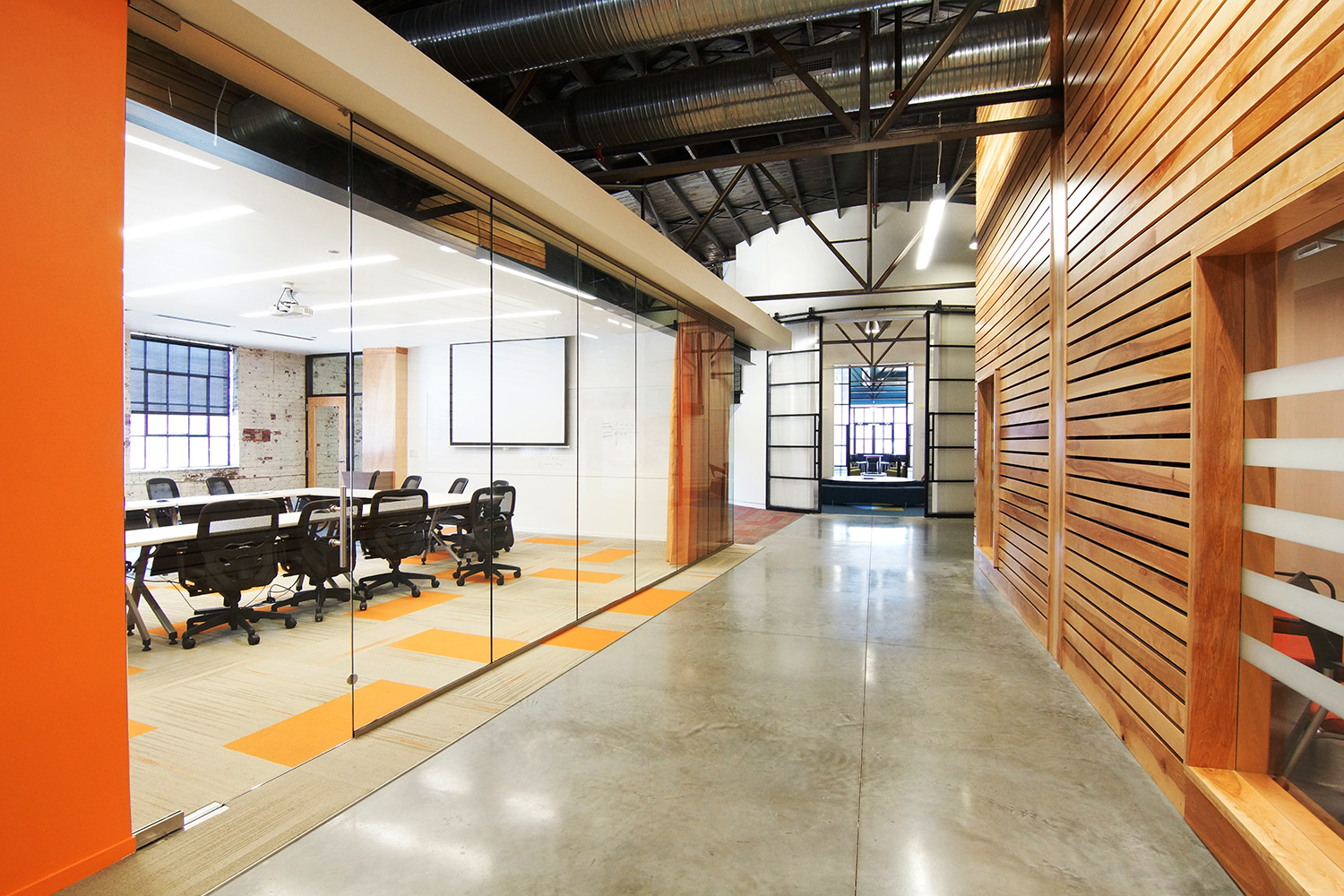 Interior of Emma's offices in the Trolley Barns: exposed steel trusses, a cedar slat wall and polished concrete.